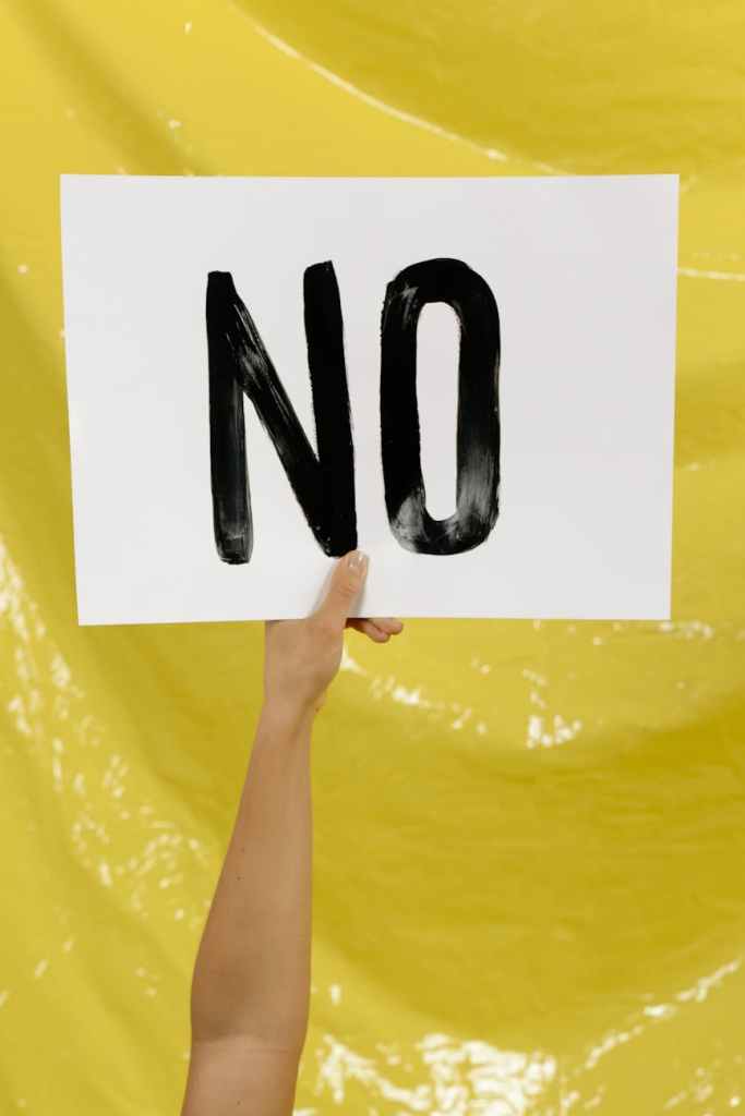A woman holding up a sign that says "no"