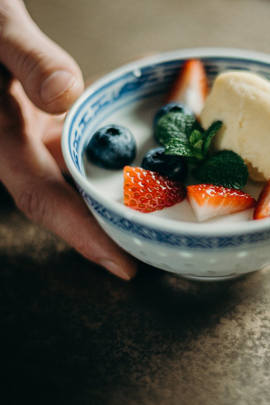 A mom holding a bowl of yogurt with strawberries, blueberries and basil