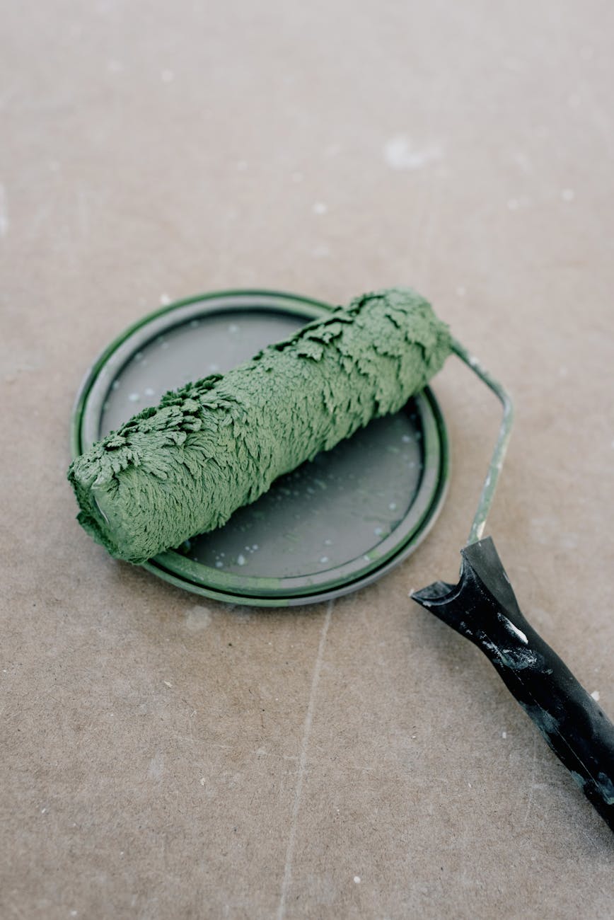 A roller paint brush covered in warm green paint