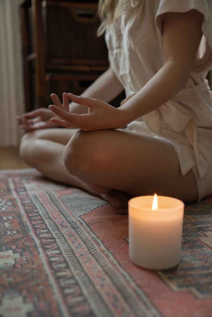 a woman meditating by candlelight