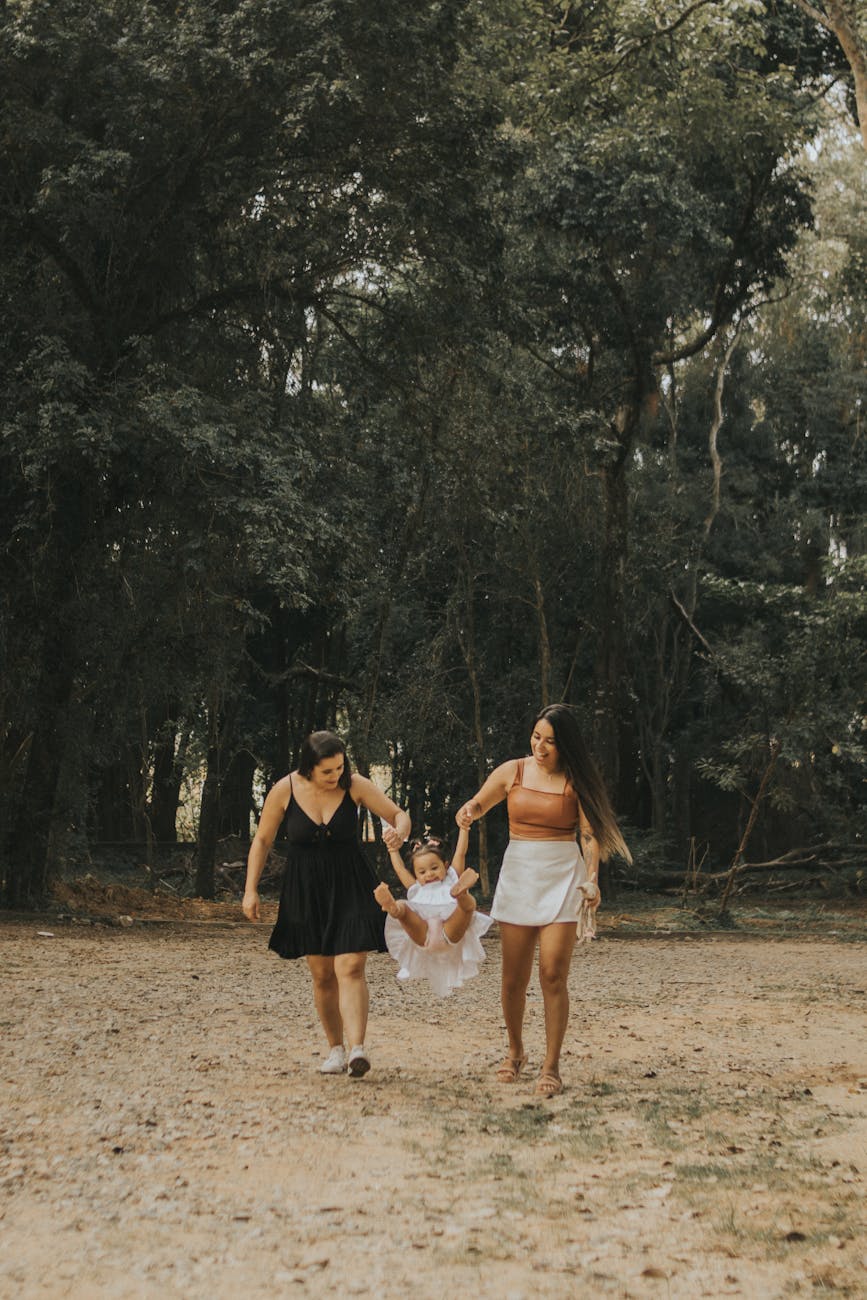 a mom and grandma swinging their daughter as they walk 