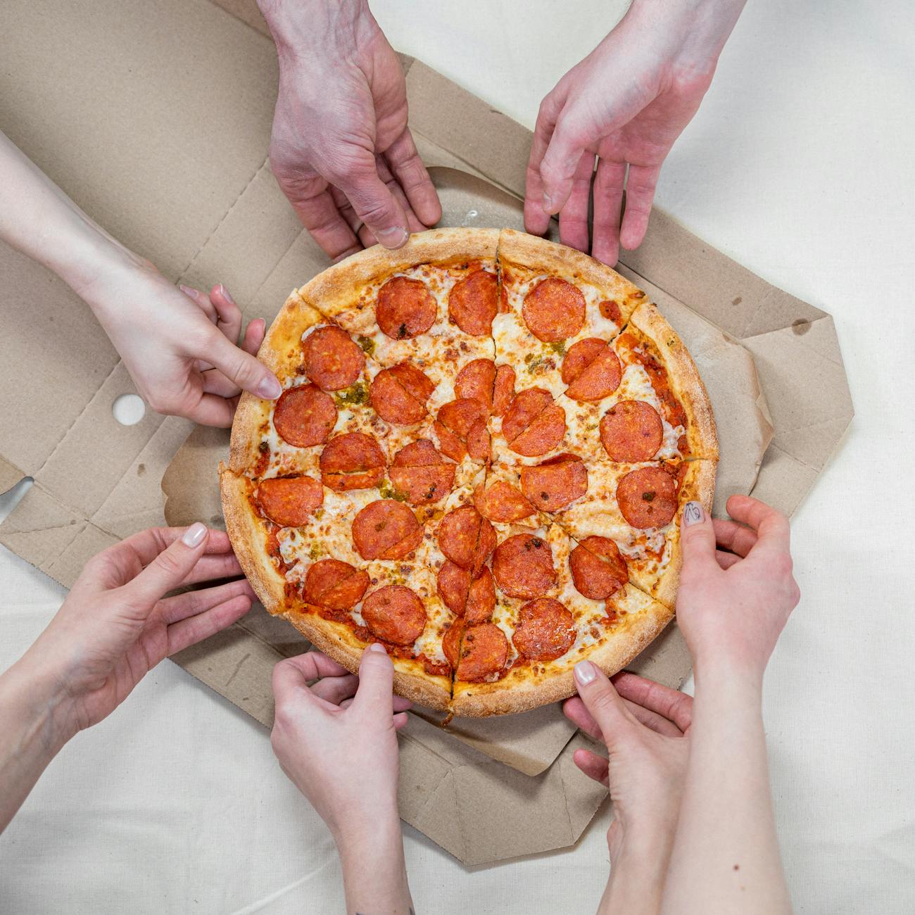 Hands grabbing slices of pizza