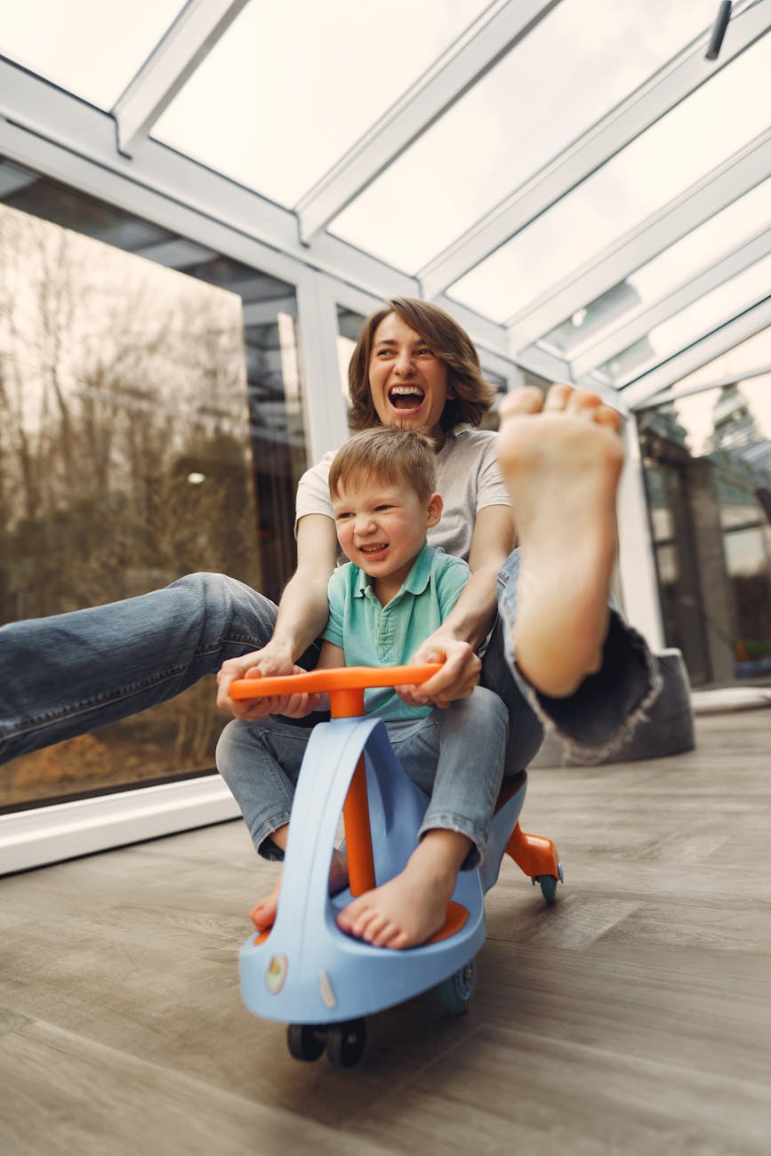 Mom riding on a toy car with her son laughing