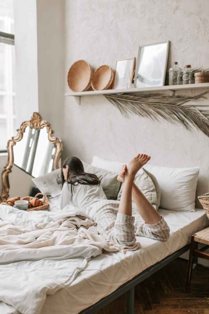 a mom lying down on her cozy bed reading the paper