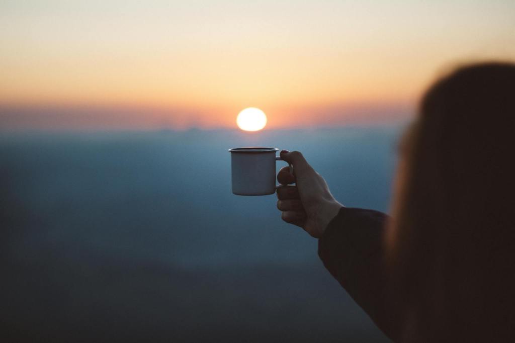 woman watching the sunrise with a cup of coffee