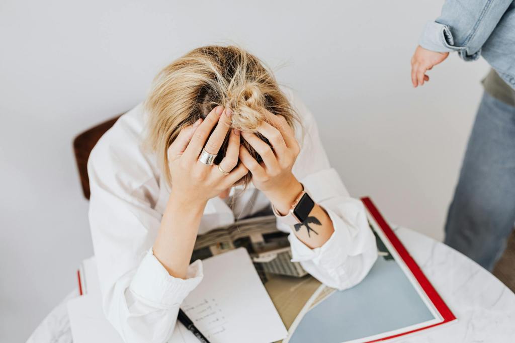 Exhausted mom at kitchen table surrounded by end of school year paperwork